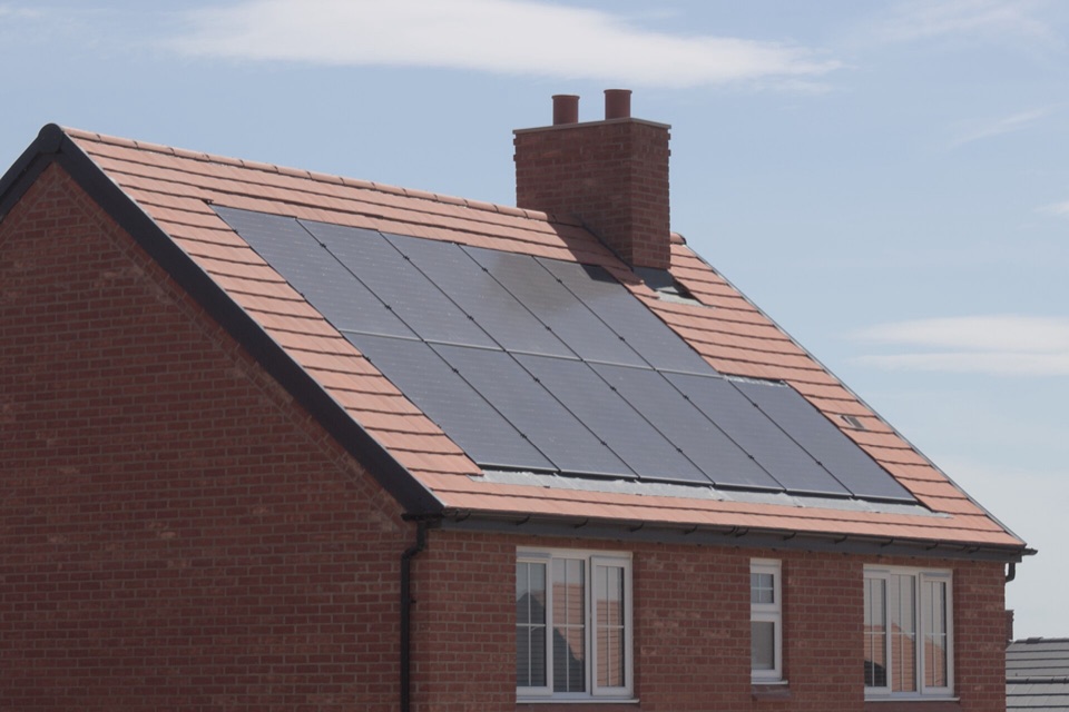 Black solar panels covering the tiled roof of a red brick house in England
