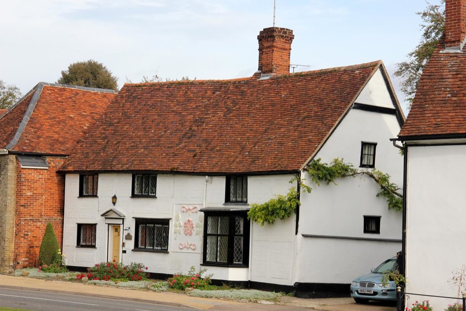 A row of white rendered cottages with clay tiled roofs at Cavendish in Suffolk