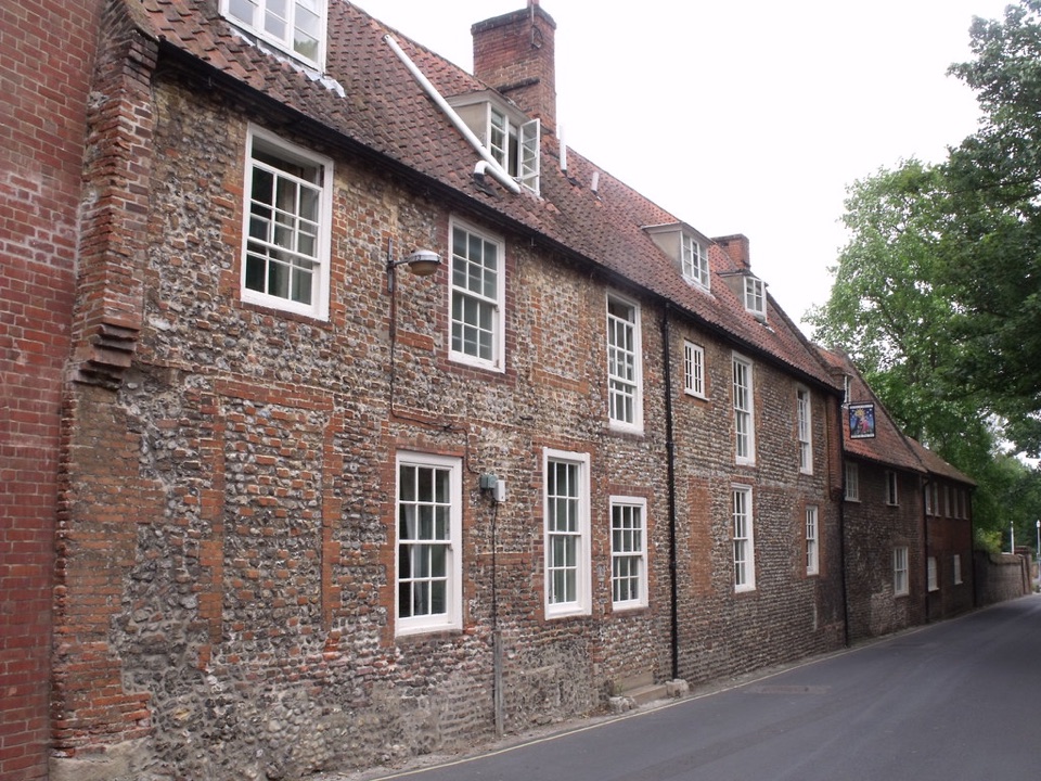 A terrace of flint and brick houses with sash windows on a village street in Norfolk