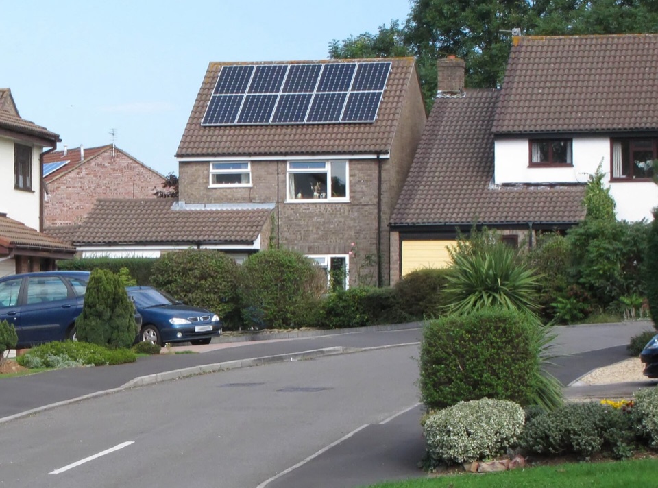 Solar panels on the roof of a detached house on a suburban street in England